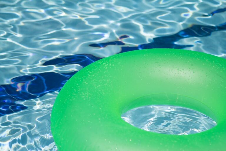 Bright swim ring floating in backyard pool - beach vacation vs staycation swimwear picks