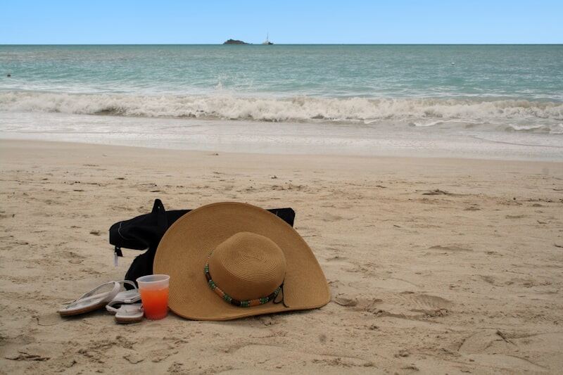 Beach vacation essentials with hat and sunglasses on tropical sand