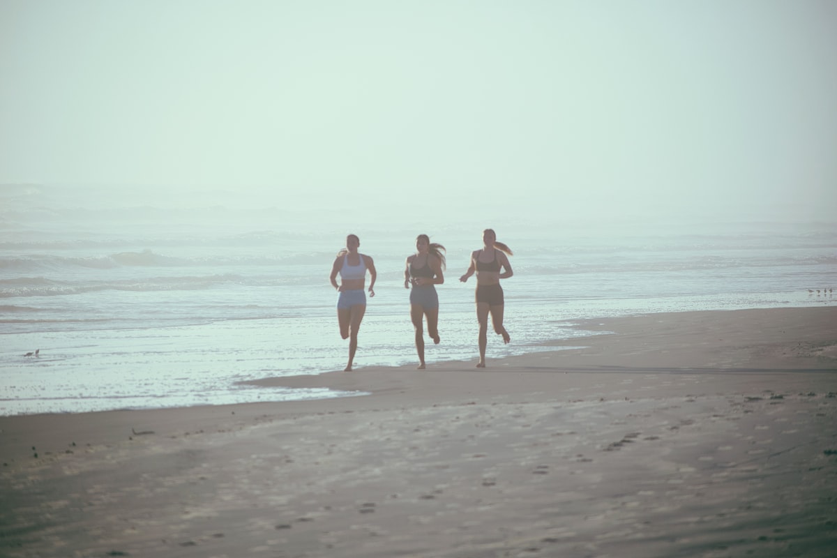Runners exercising along the beach near ocean waves