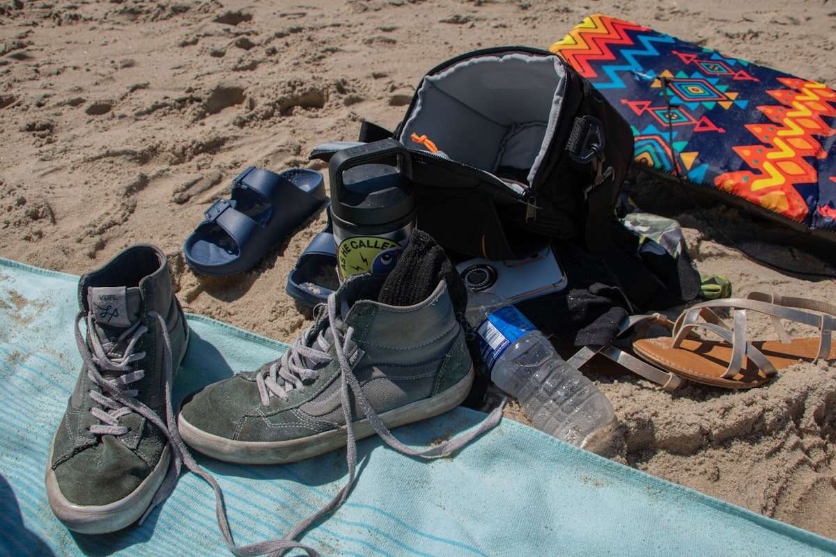Beach gear and packing essentials laid out on sand for vacation planning