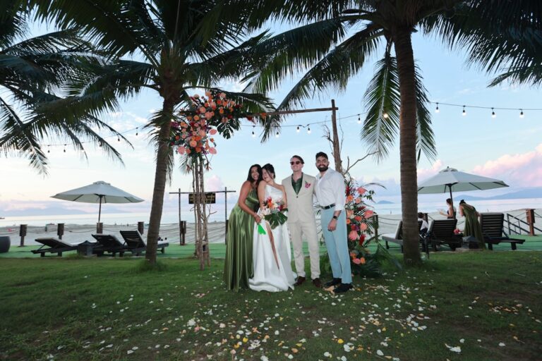 Wedding party posing under palm trees at a tropical beach wedding ceremony