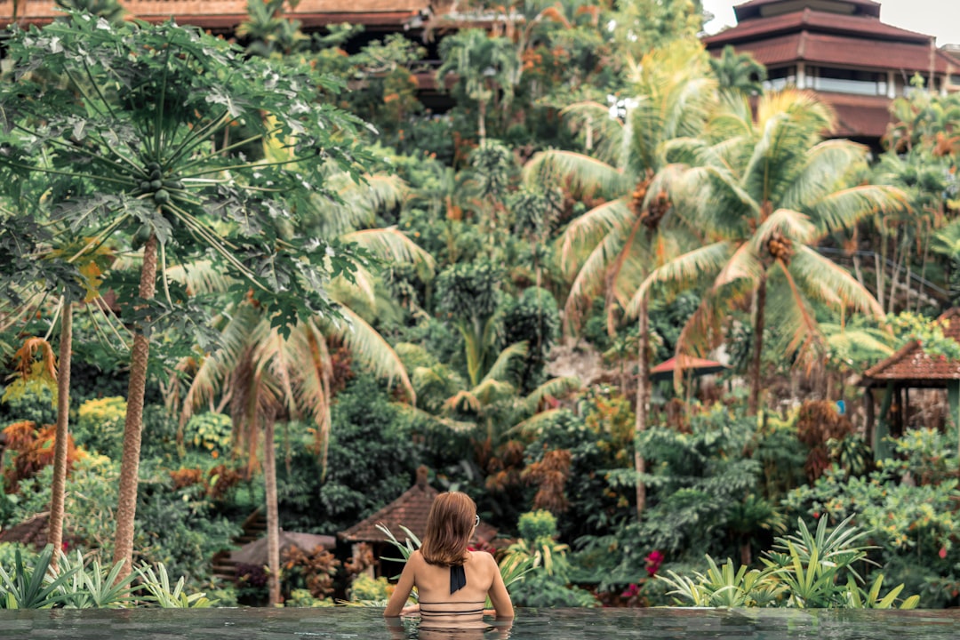 Woman relaxing in tropical infinity pool overlooking palm trees resort swimwear