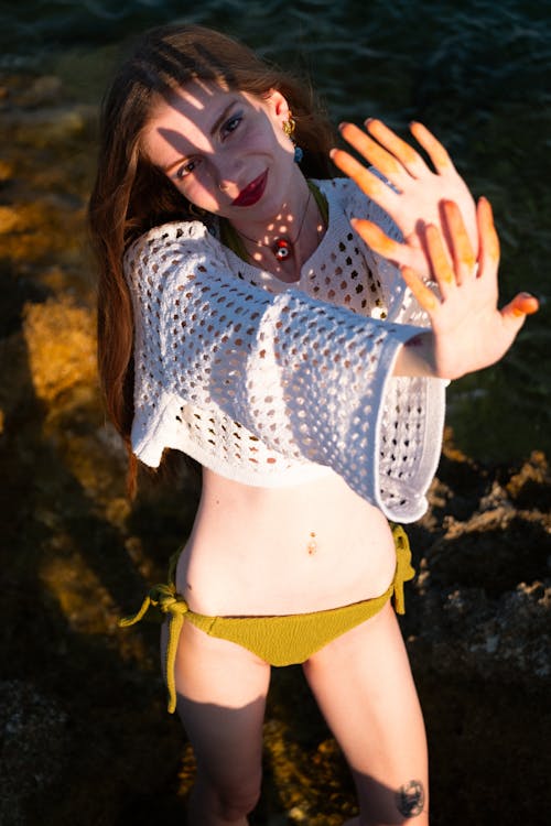 Crochet beach cover up styled over a green bikini at sunset