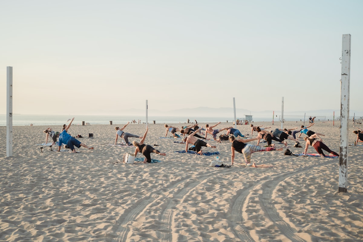 Group beach yoga class at sunset with ocean backdrop