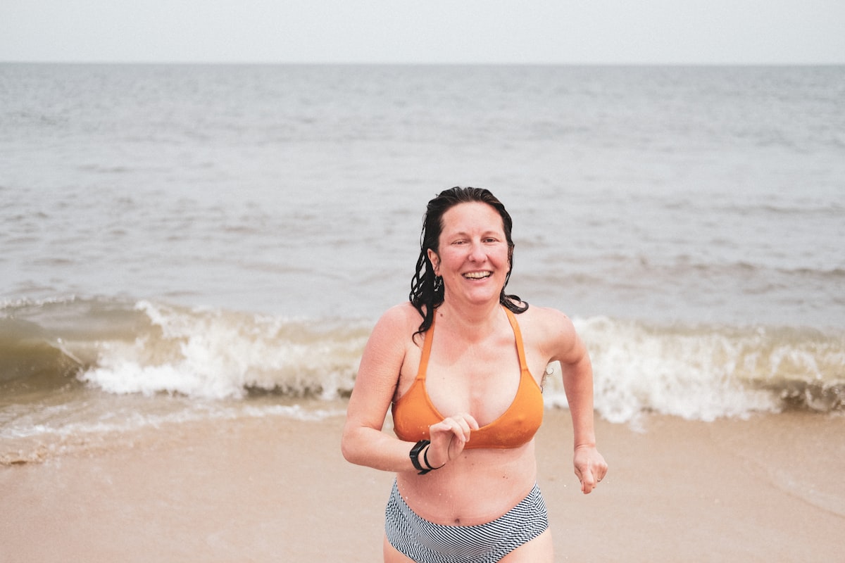 Woman in orange bikini standing on beach ready for workout