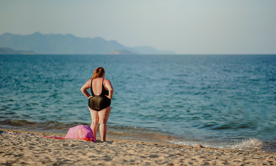Woman in black swimsuit standing on serene beach shoreline