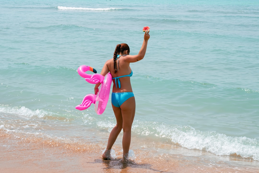 Woman wearing pink swimsuit with beach inflatable showcasing fun summer swimwear style