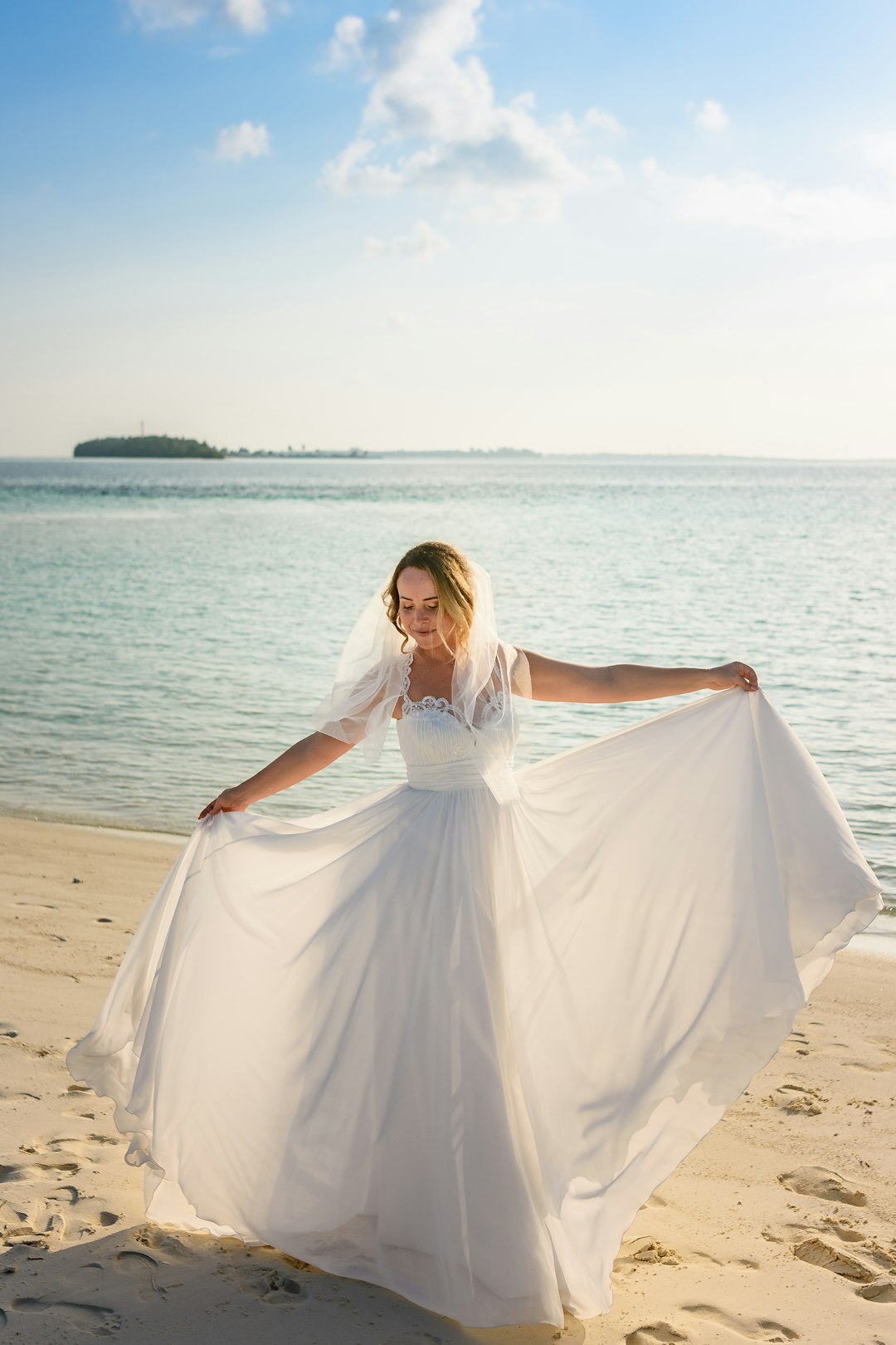 Woman in a flowing seaside dress standing on a beach perfect for beach wedding outfit inspiration