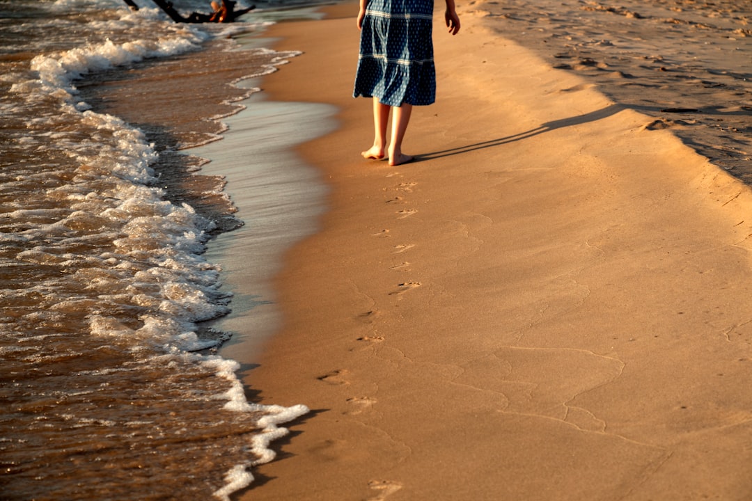 woman in white bikini walking barefoot on sandy beach embracing summer eco-friendly swimwear lifestyle