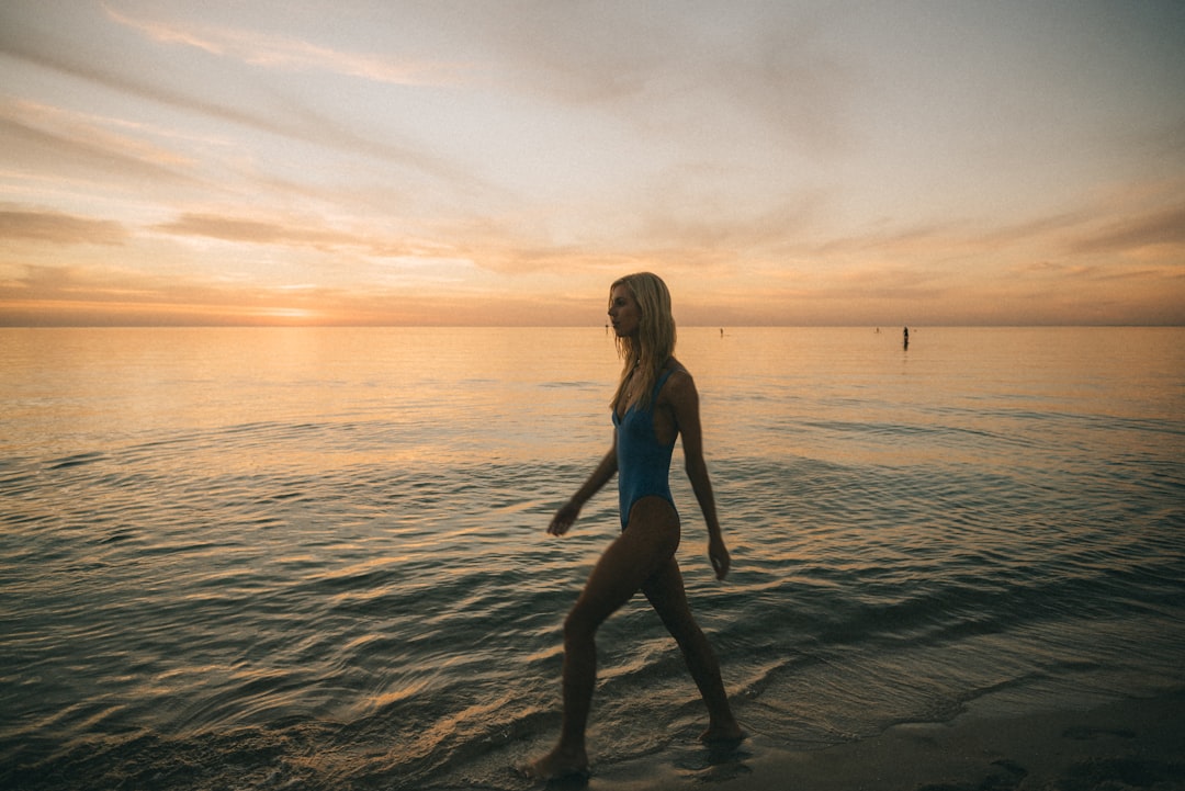 Woman walking confidently on beach in bikini at sunset