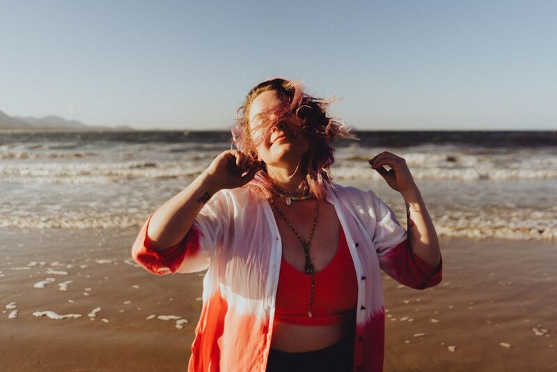 woman smiling at the shore while learning how to feel confident in a bikini