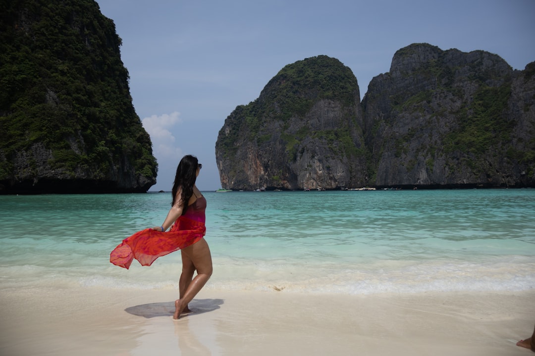 A vibrant shot of a woman posing confidently in red swimwear at the stunning Maya Bay, Thailand. The turquoise waters, white