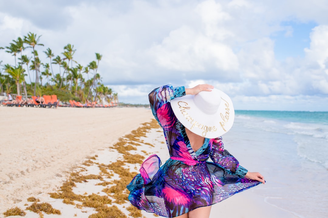 Woman wearing honeymoon dress and white hat walking on the beach