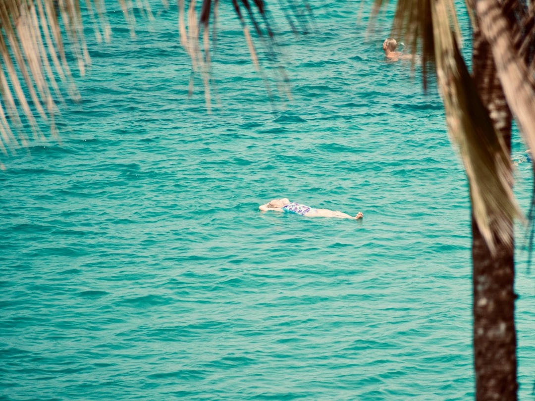 A person floats on their back in turquoise ocean water.