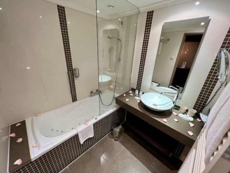 Modern hotel bathroom with elegant bathtub, glass shower, and vanity mirror.
