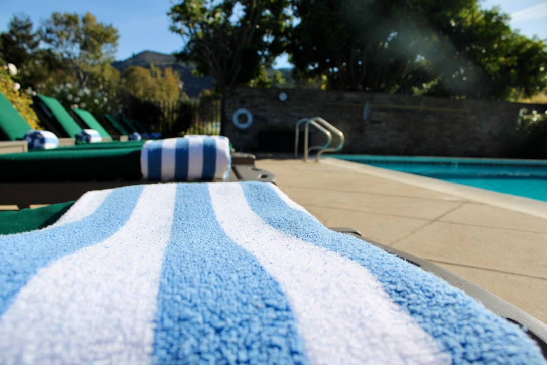 Blue and white striped towel on lounge chair by pool.