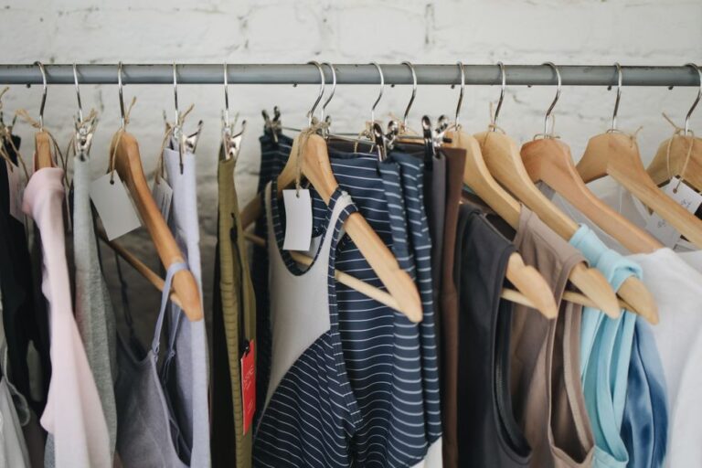 A variety of casual clothing items hanging on wooden hangers in a fashion boutique.