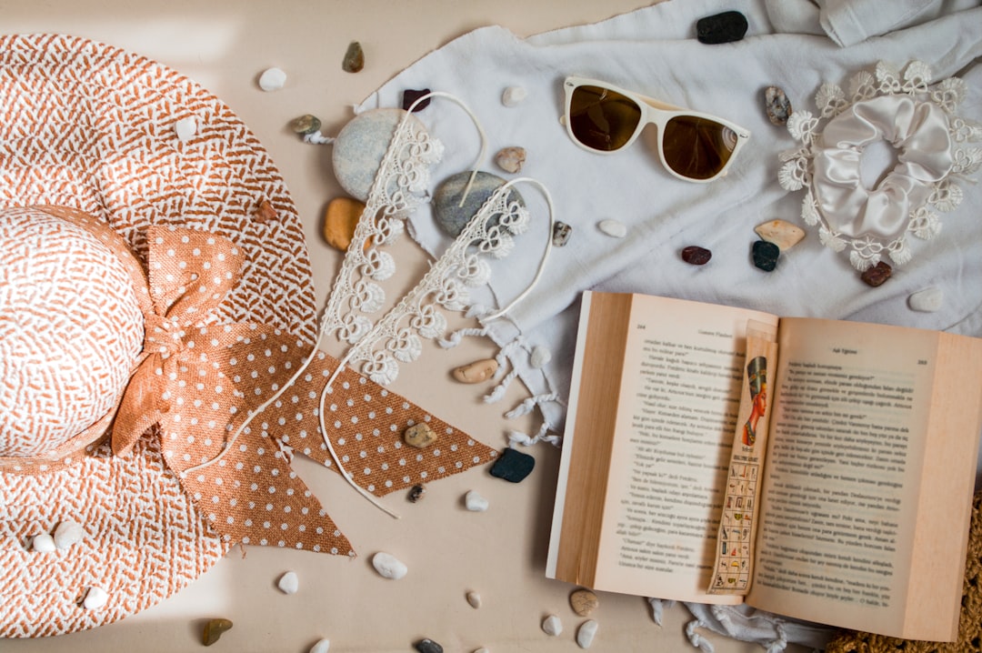 Summer time beach vibe accessories flat lay, barefoot anklets, sun glasses, beach stones, open book