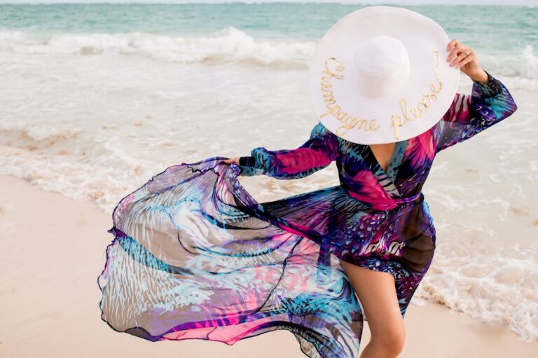 Beautiful girl wearing a flowy colorful dress and hat with "champagne please" on it, walking on the beach in Punta Cana