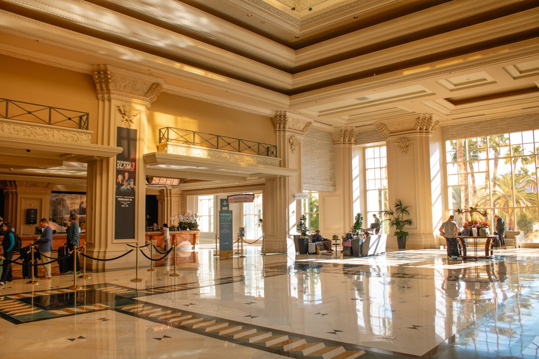 Sunlight streams through large windows, illuminating the polished floor and highlighting tall, ornate columns of the grand ho
