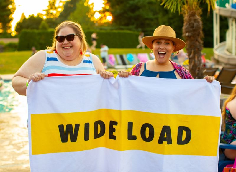 Two women celebrating body confidence in swimwear at the pool