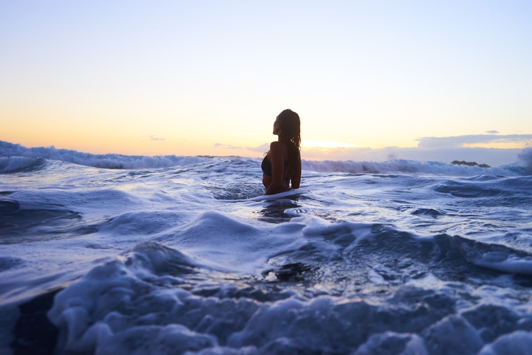 Solo female traveler in ocean at sunset