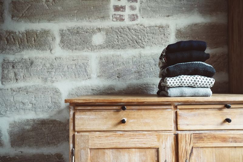 Folded clothes stacked on wooden dresser — store a swimsuit flat between wears