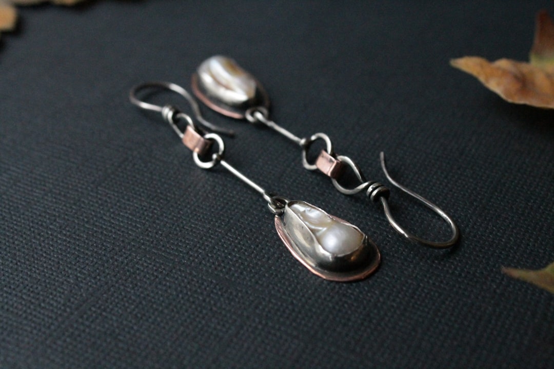 a pair of earrings with pearls hanging from them