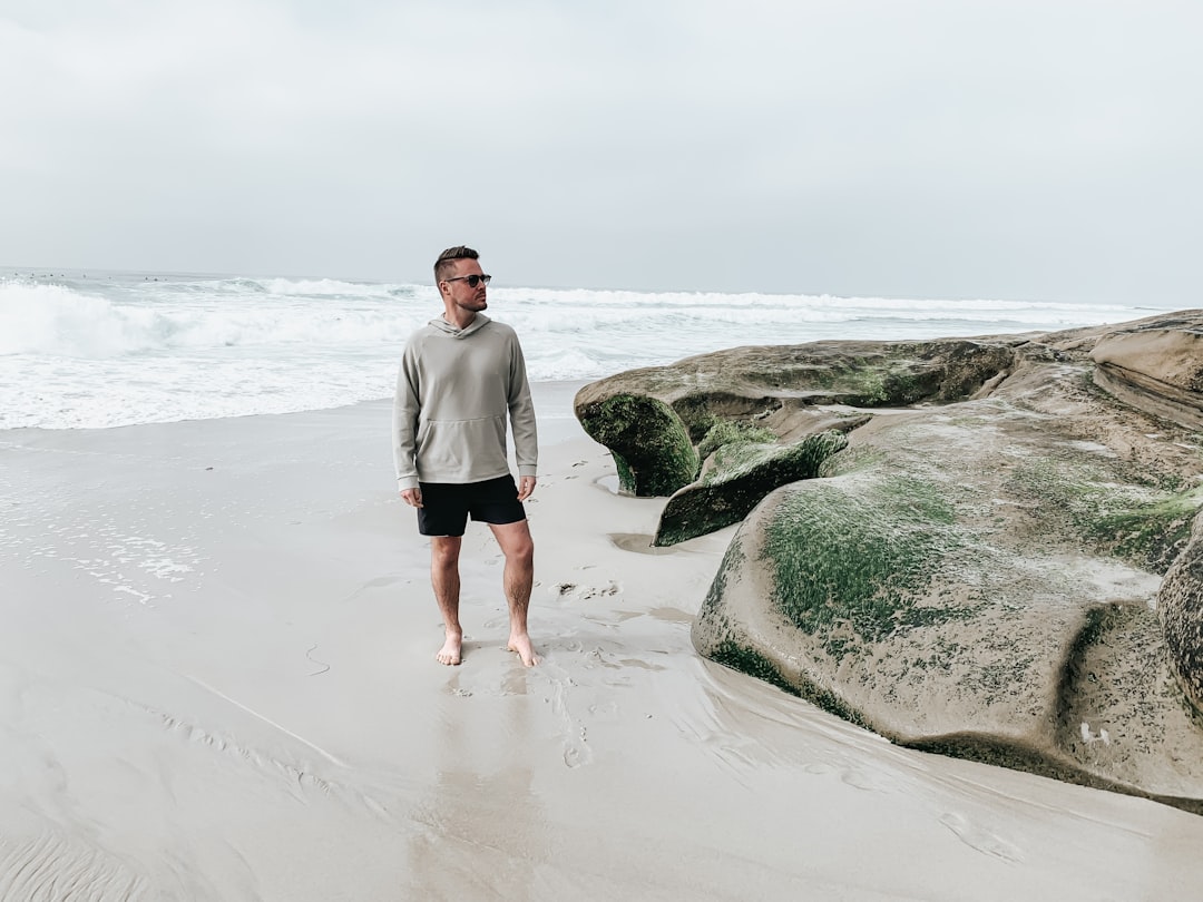 man in white long sleeve shirt standing on beach during daytime