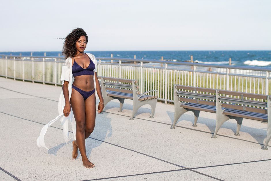 woman in a cover-up walking the boardwalk by the ocean