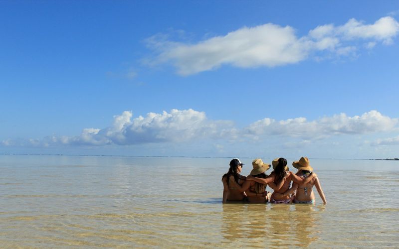Four friends wading in shallow water enjoying a chafe-free summer beach day