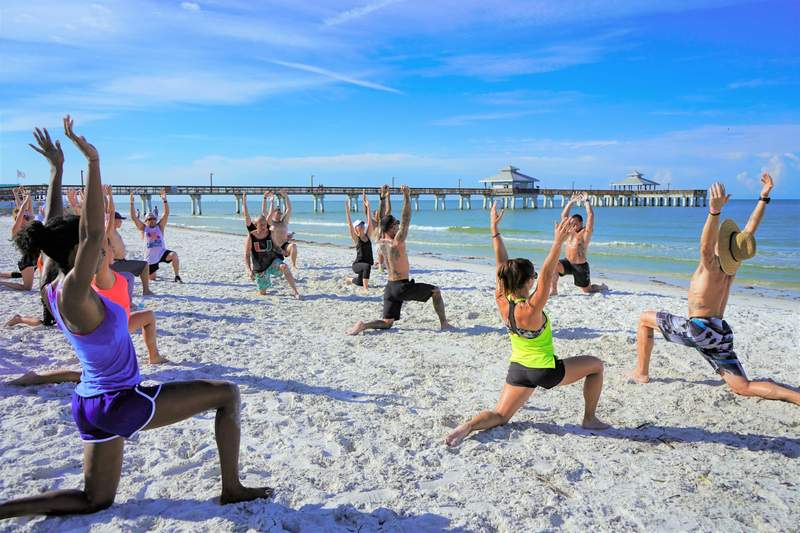 Group beach workouts with lunges in swimsuits on the sand