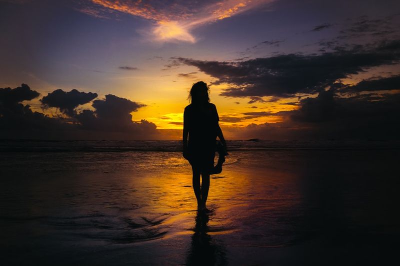Woman walking into the ocean at sunset showing bikini confidence over 40