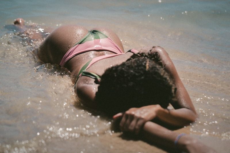 woman in pink bikini in shallow beach water enjoying summer