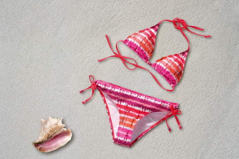 Colorful tie-dye mix and match bikini set laid flat on sand