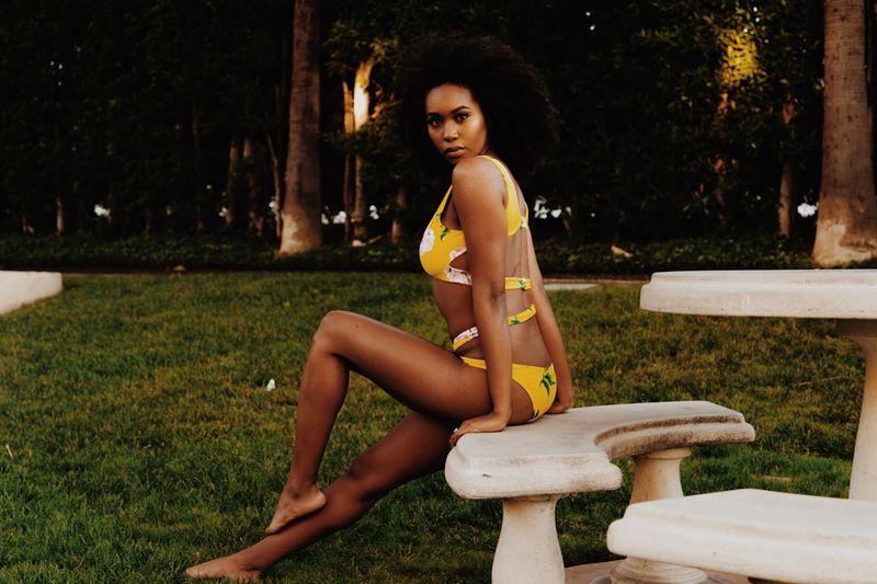 Woman wearing a cutout bikini in a garden at golden hour