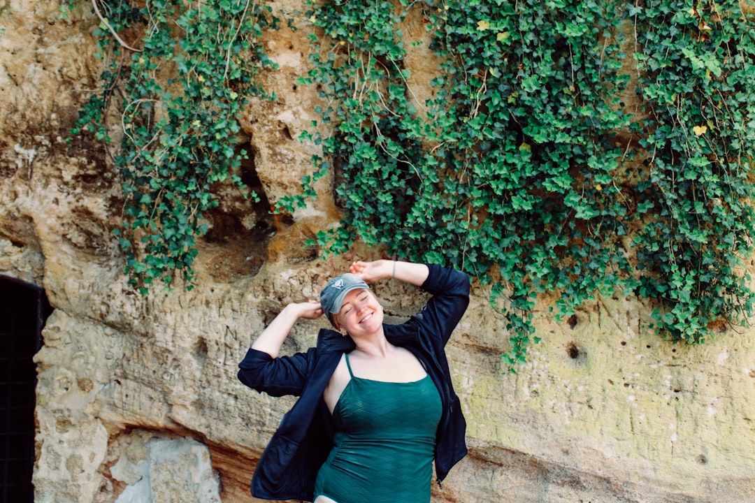 a woman standing in front of a rock wall