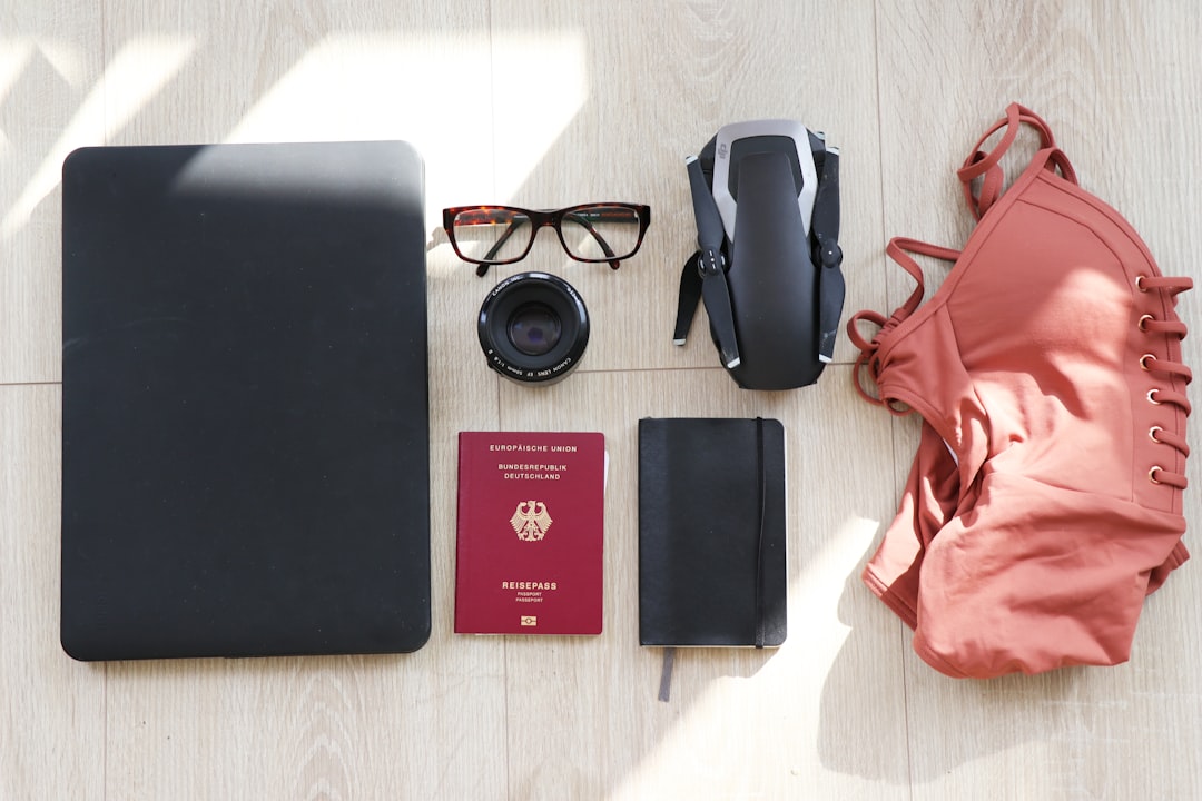 laptop, passport, sunglasses and swimsuit packed for a beach trip