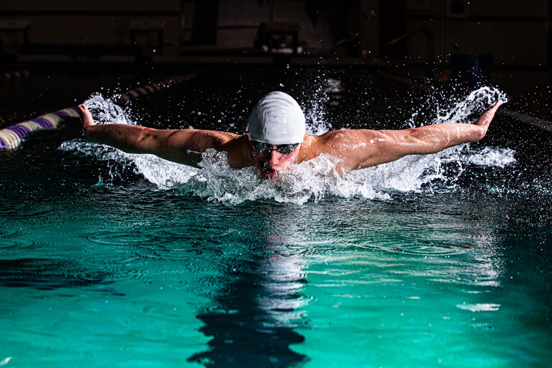 Male swimmer racing the butterfly stroke in athletic pool.