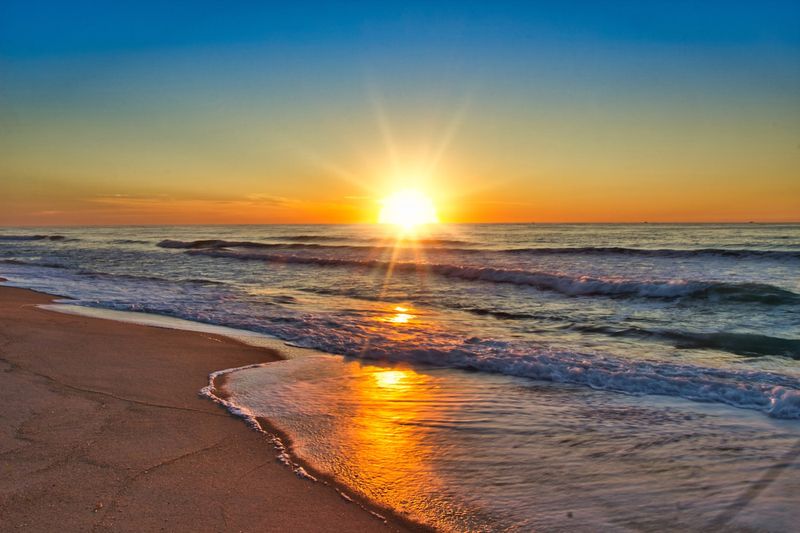 sunrise over an empty beach at the start of a perfect beach day