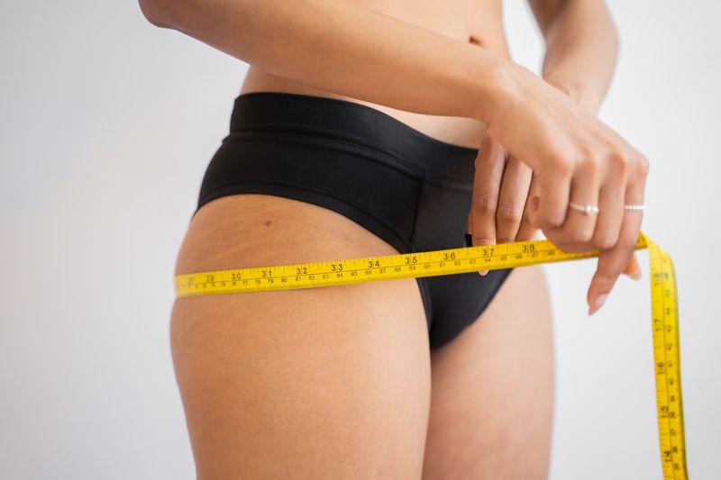 woman taking body measurements for swimsuit size guide online shopping
