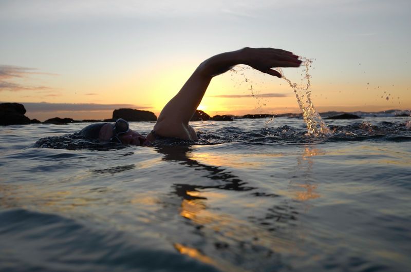 Open-water swimmer at sunset, swimwear fabric that reduces chafing