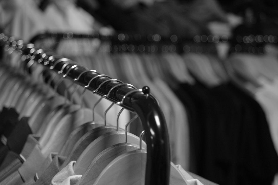 Black and white close-up of clothing racks with hangers in a retail store.