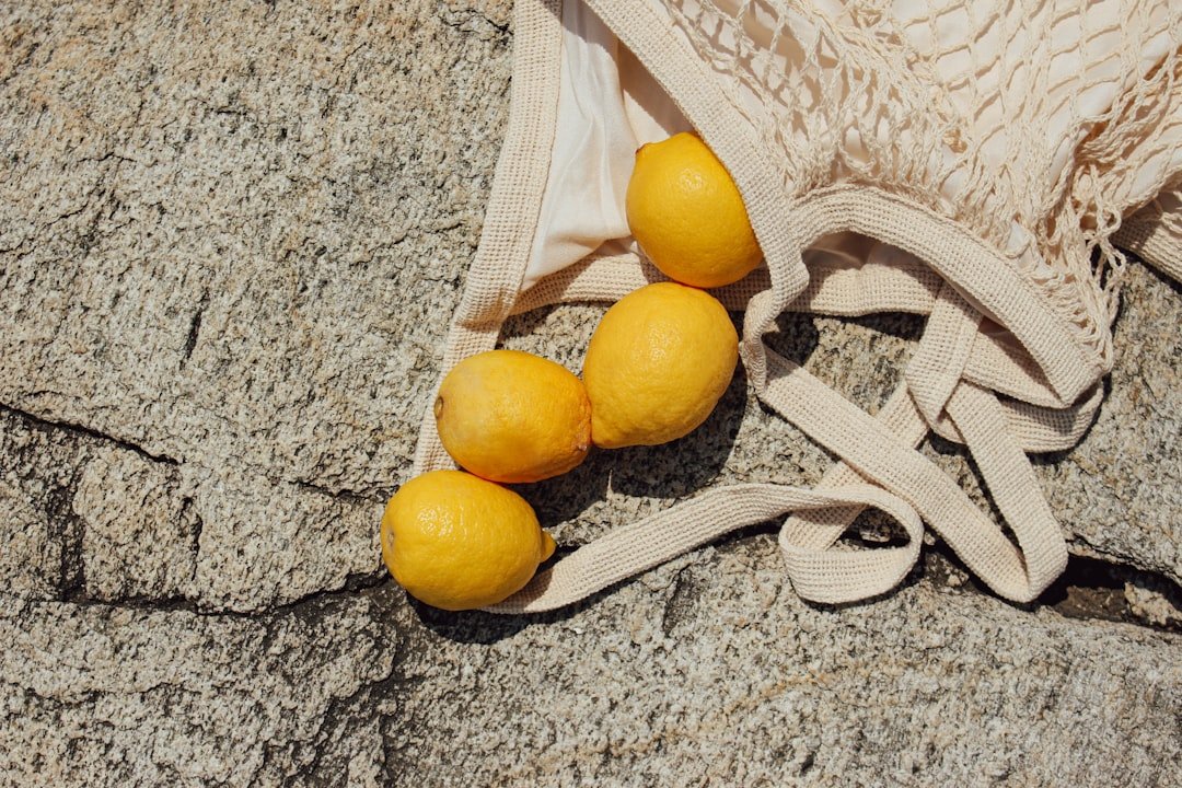 Lemons have scattered from the eco-bag onto the stone, creating a bright and unexpected scene.