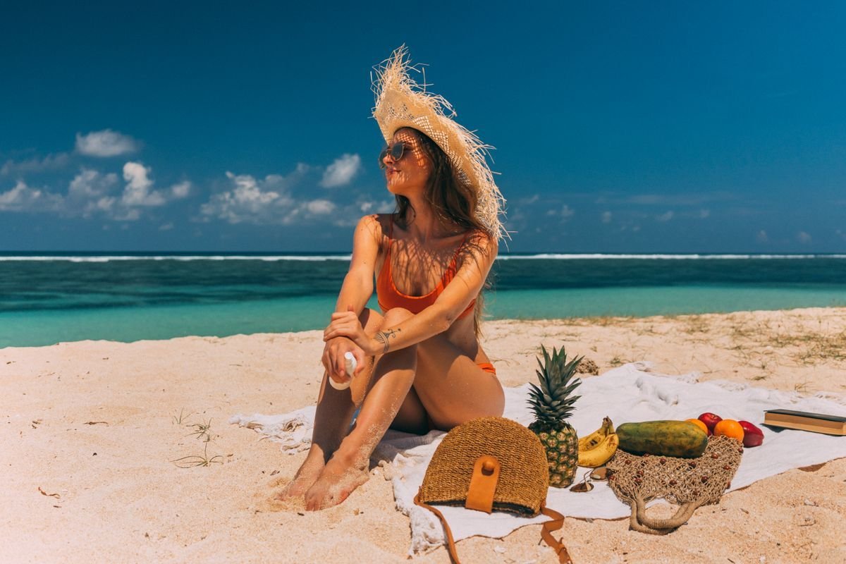 Woman in orange tie-side bikini bottoms relaxing on tropical beach