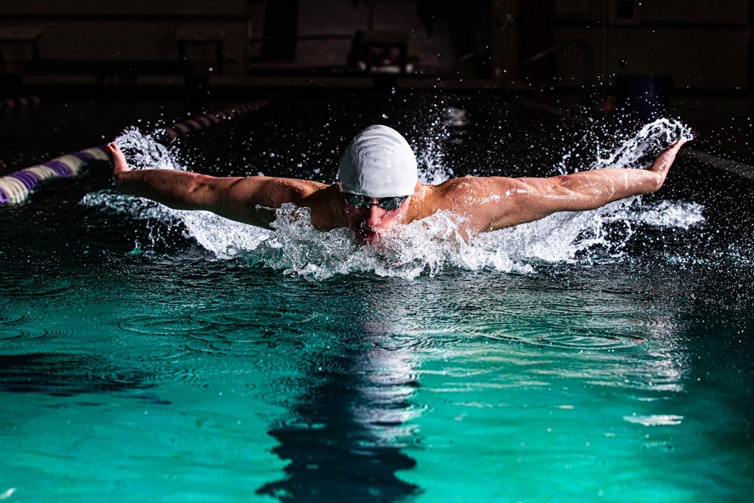 Male swimmer racing the butterfly stroke in athletic pool.