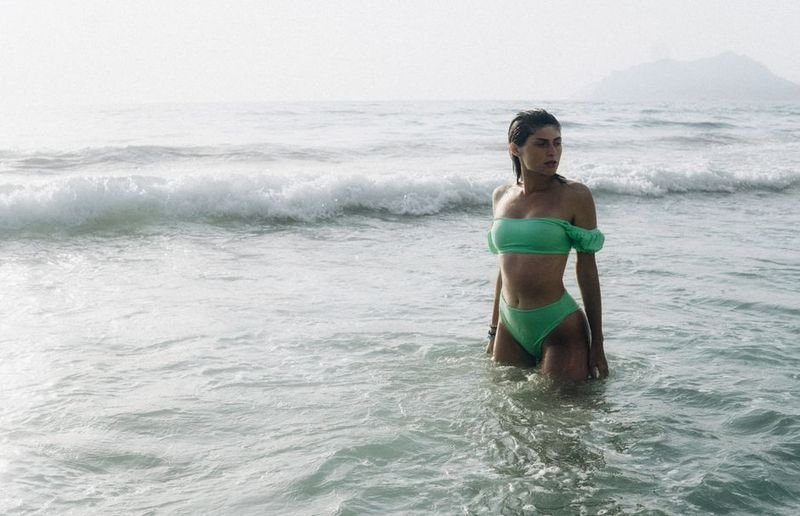 Woman in green side-tie bikini in ocean water showcasing tie bikini style