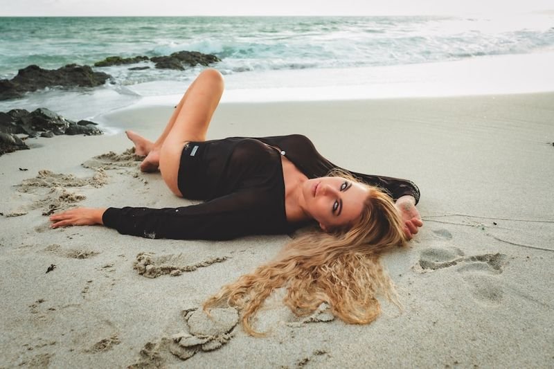 woman in long-sleeve rash guard swimwear relaxing on sandy beach