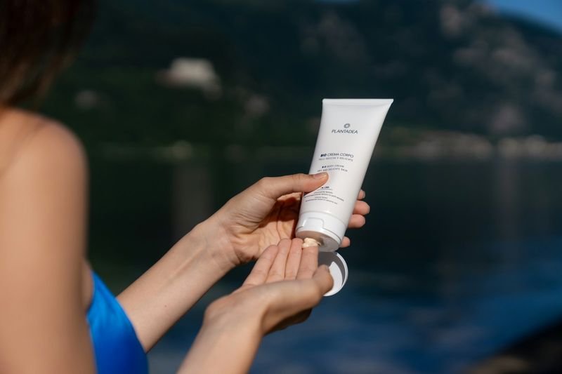 applying reef safe mineral sunscreen to arm before swimming at the beach