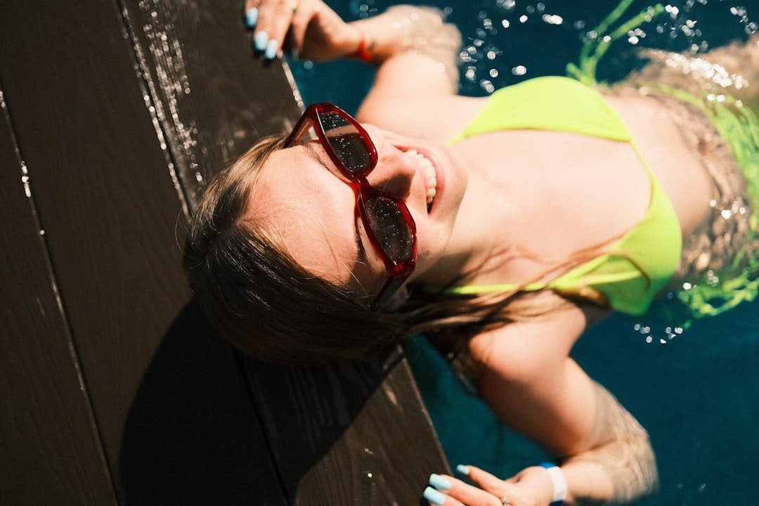 Smiling woman in yellow bikini and sunglasses in water